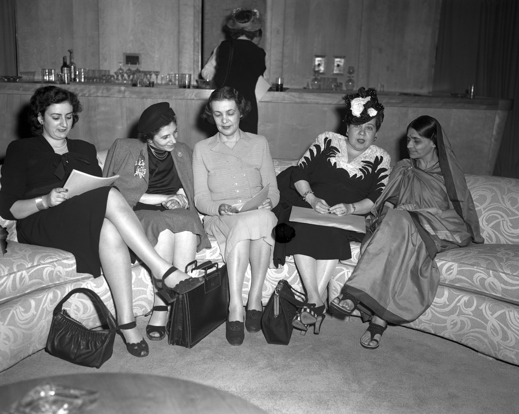 Cinq femmes assises sur un canapé en train de consulter un document