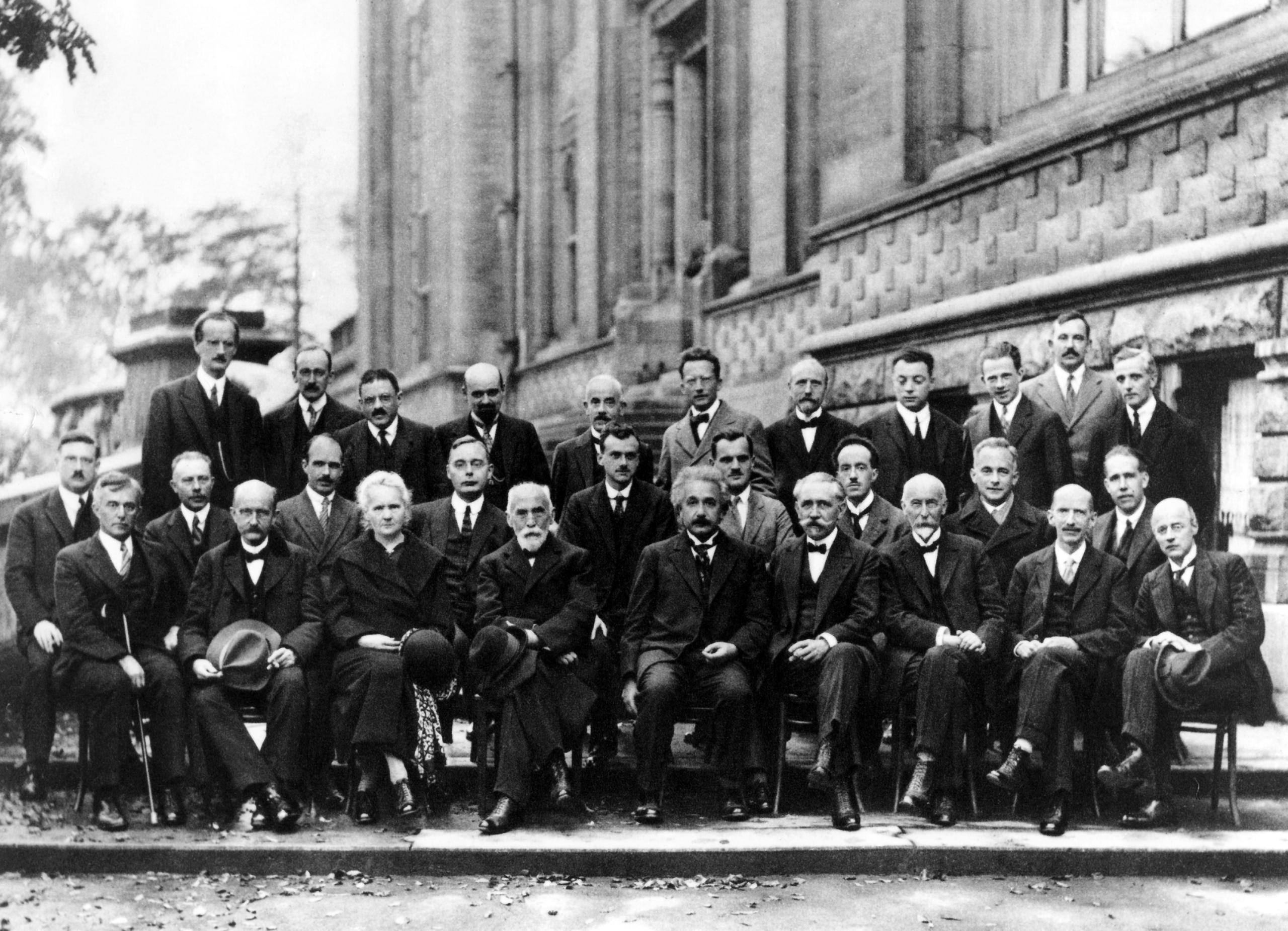 全球物理学界的顶尖人物齐聚1927年在布鲁塞尔举行的索尔维会议。在这一年，爱因斯坦(中间)和尼尔斯·玻尔(第二排最右)展开了一场足以载入史册的的论战。合影中还有量子物理的先驱马克斯·普朗克(前排左二)，坐在他身旁的居里夫人是与会的唯一女性。