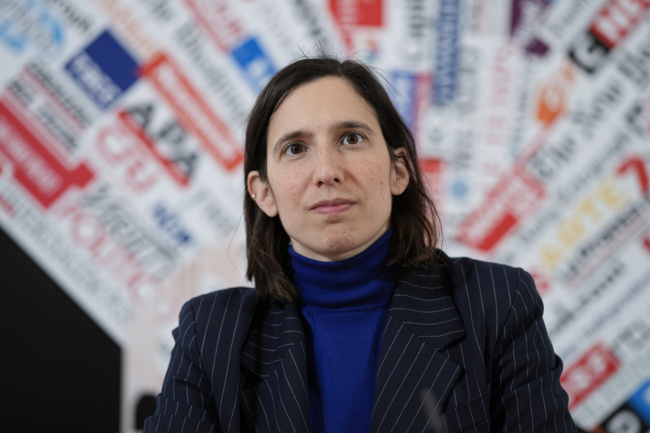 mezzo busto di donna sulla trentina in blazer nero e dolcevita blu scuro. Capelli neri fino alle spalle lisci