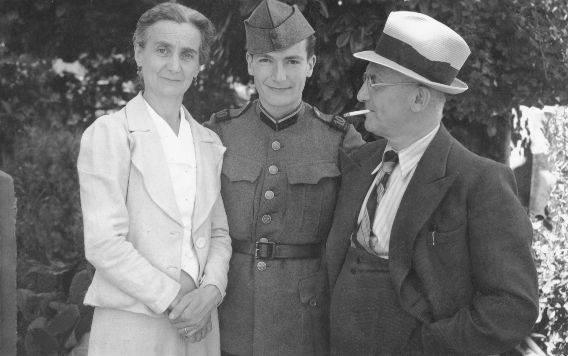 A young man wearing an airforce uniform, standing between his mother and father.