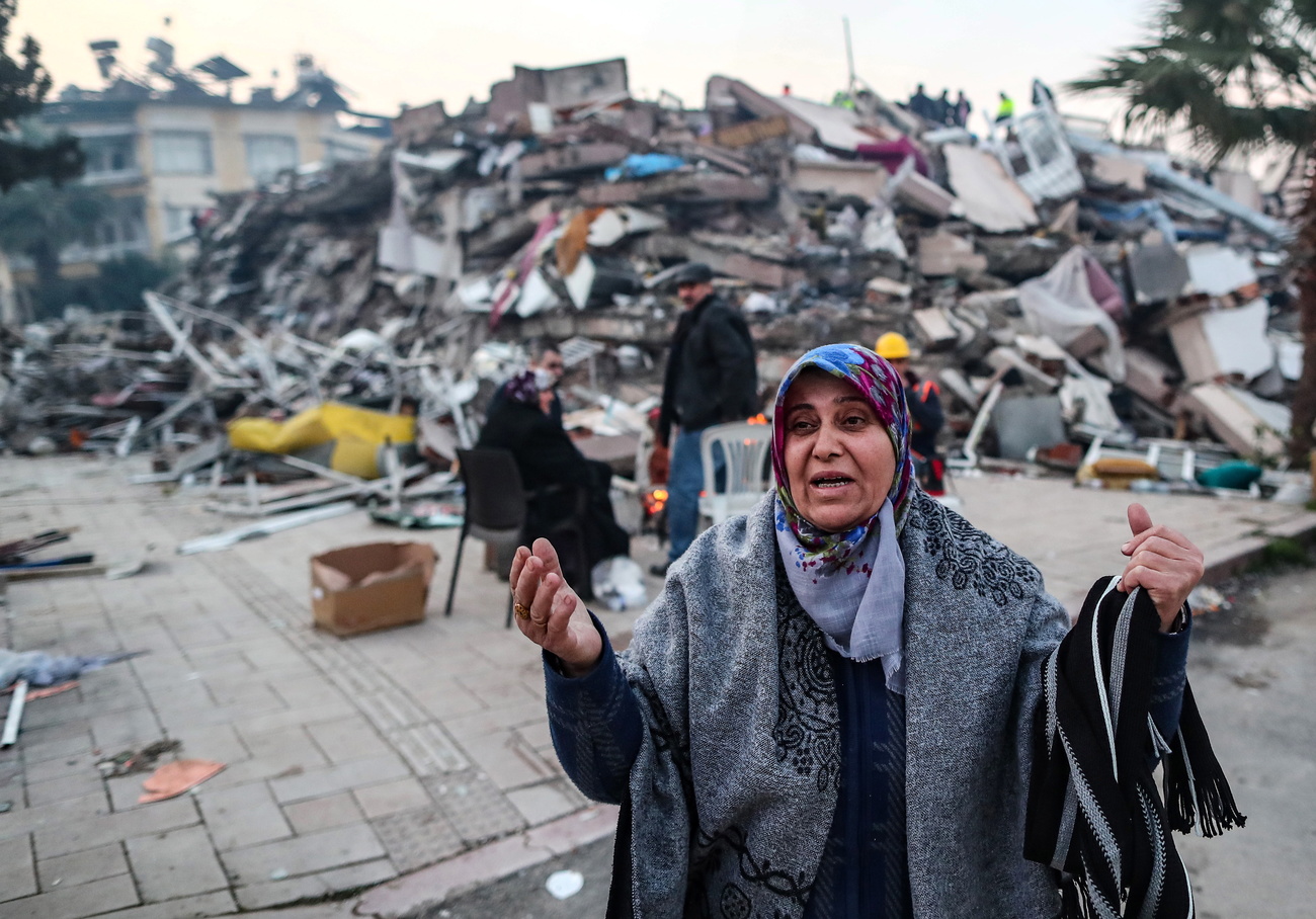 donna reagisce di fronte agli edifici crollati