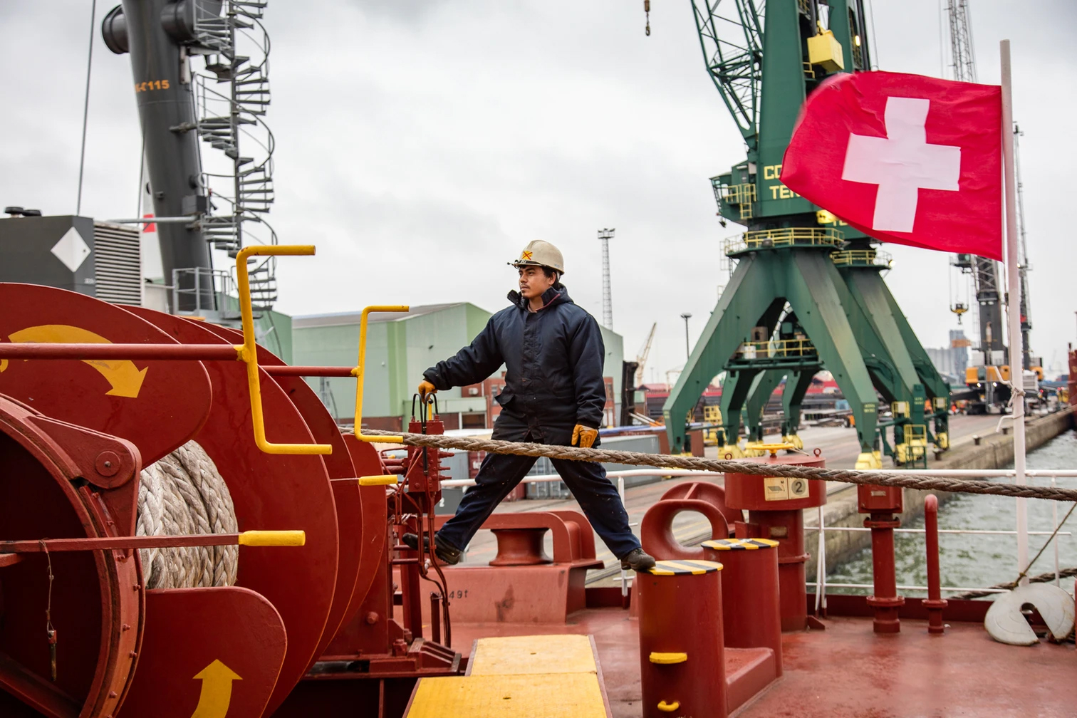 A sailor on a swiss cargo vessel holding a swiss flag