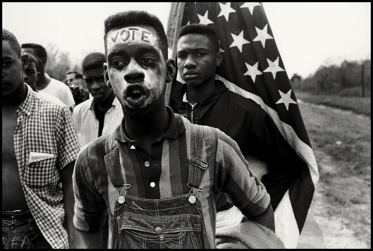 A young African American man with the word VOTE on his forehead.