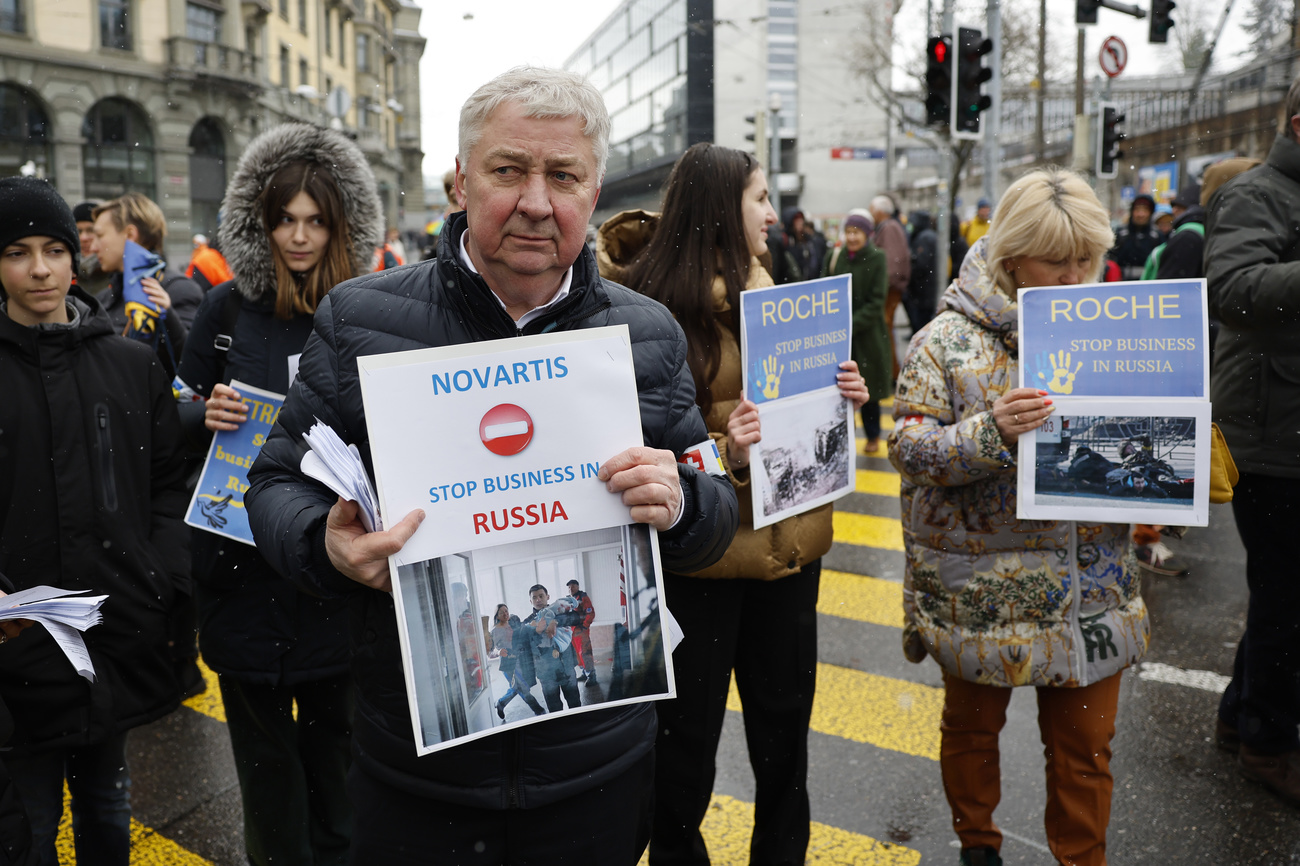 Manifestantes en Berna con pancartas pidiendo a Novartis y Roche que dejen de hacer negocios en Rusia
