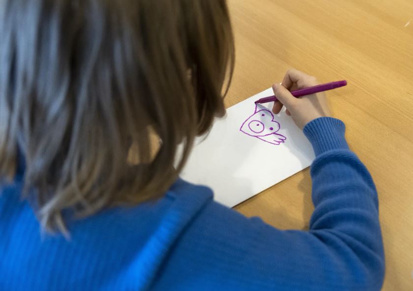 Kind, das eine Friedenstaube auf ein Blatt zeichnet