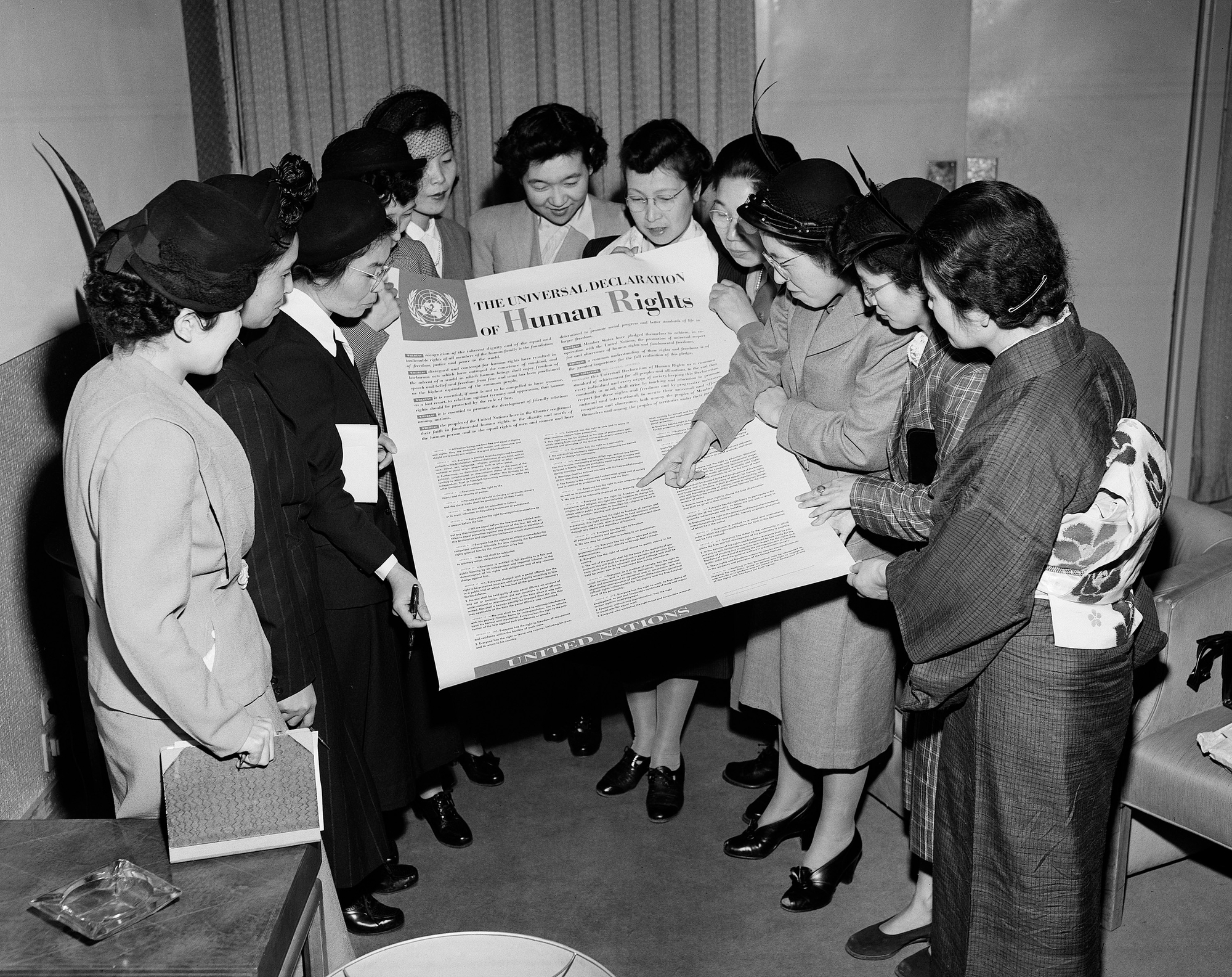 un gruppo di donne è riunito attorno a un poster che riporta il testo della dichiarazione universale dei diritti umani