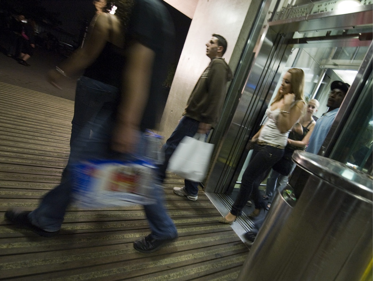 pessoas saindo da loja com pacotes de cerveja