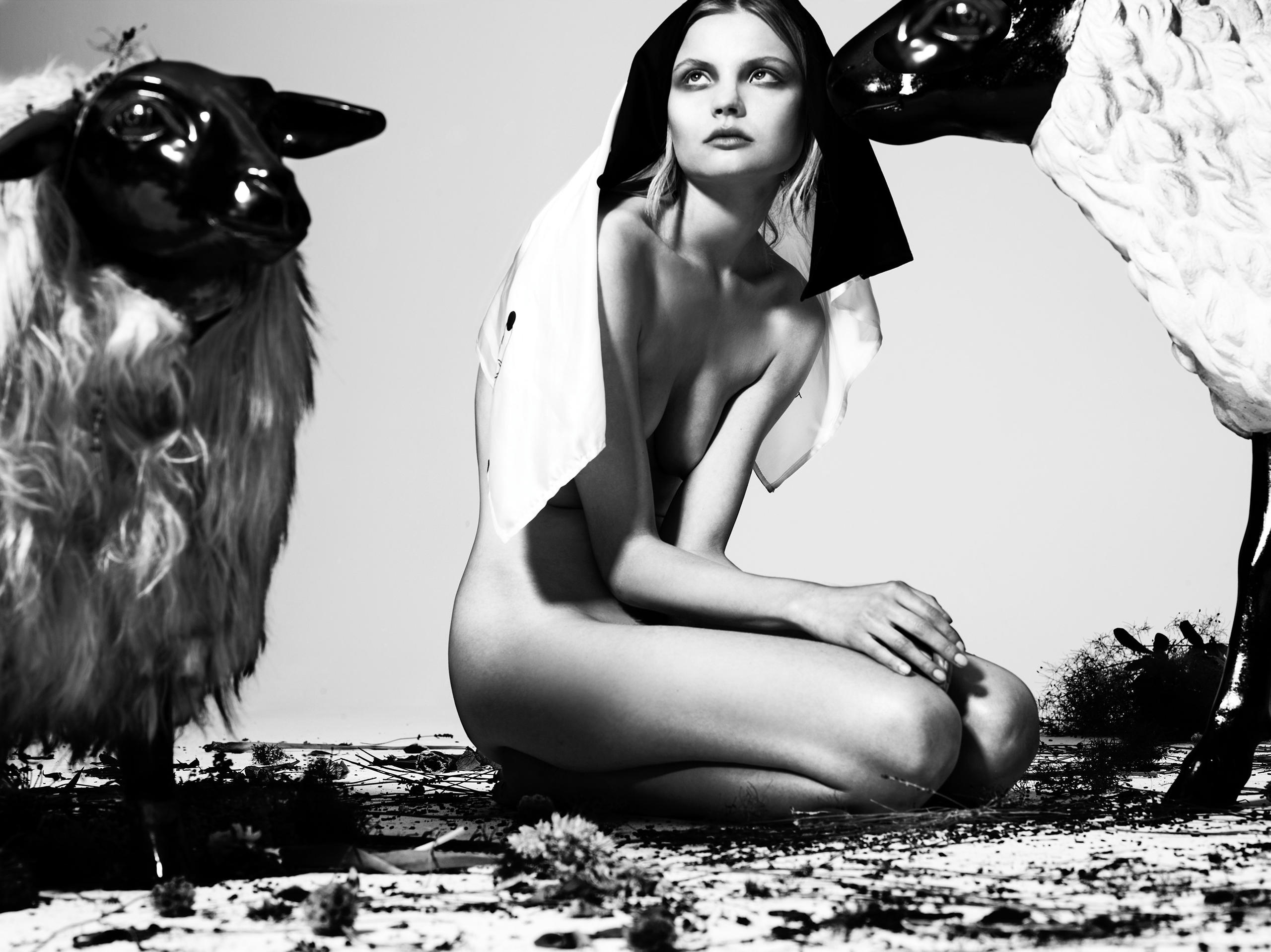 Black and white photo of model Magdalena Frackowiak and two sheeps