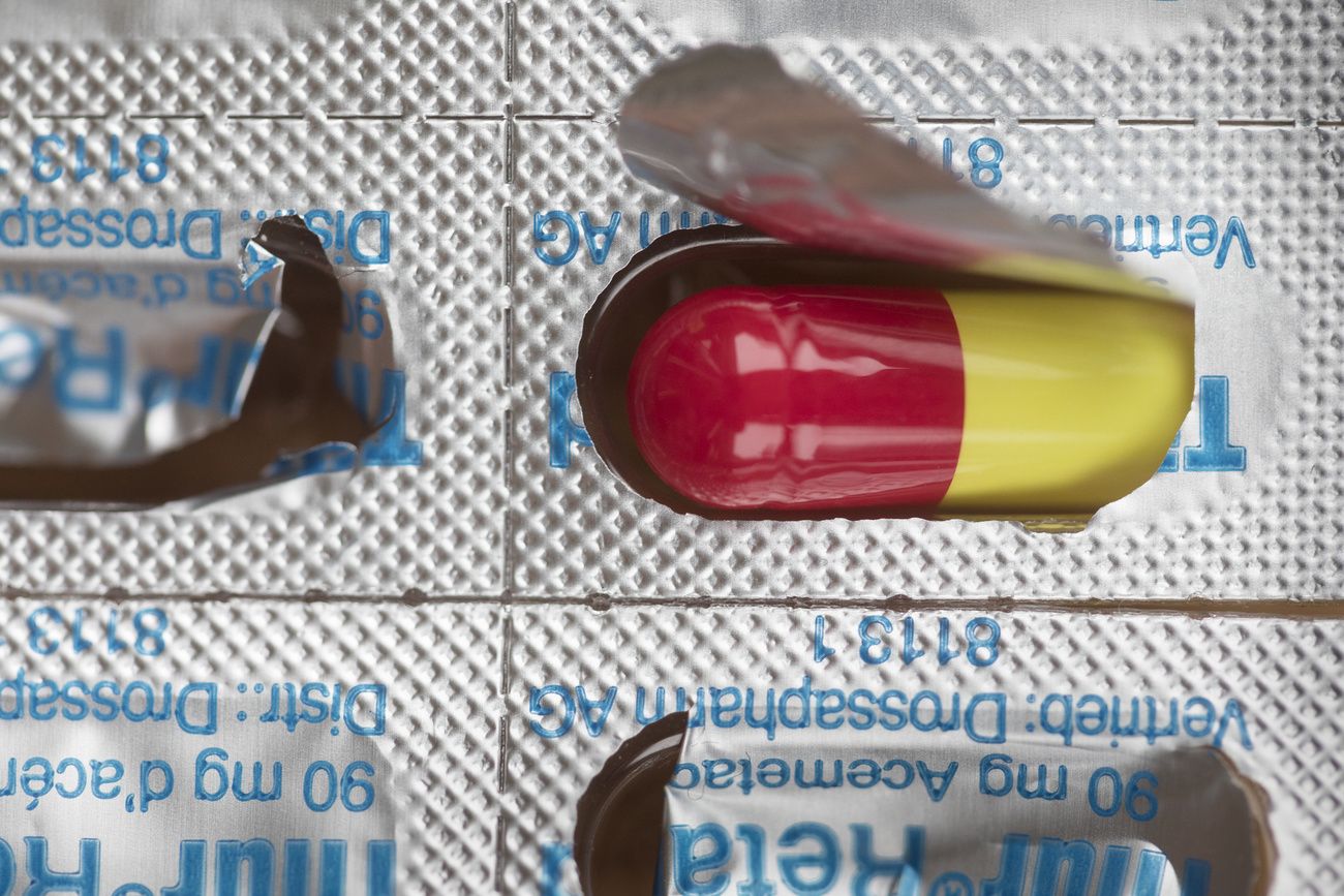 Una pillola giallo-rossa nella sua confezione.