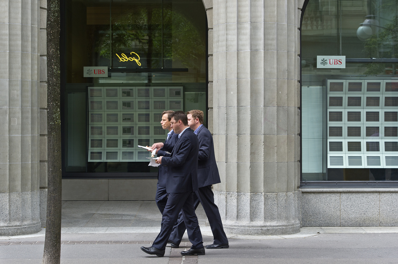 Men in suits walking past a UBS bank branch