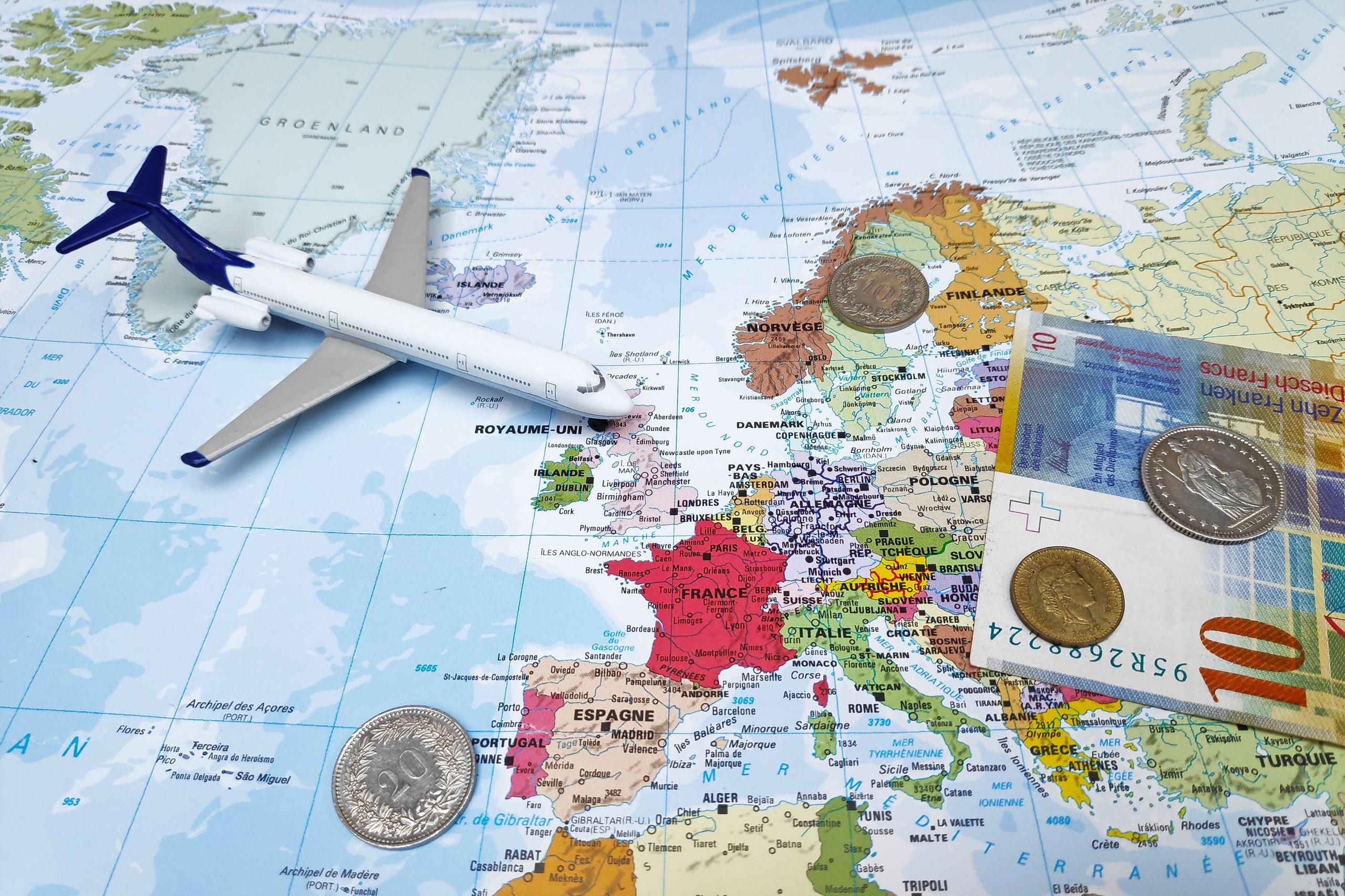 foto montaje con un mapa dibujado, un avión de juguete y dinero encima del mapa mundis
