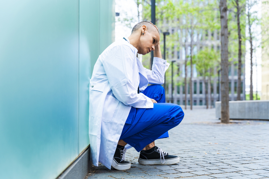 Doctor appearing stressed, kneeling.