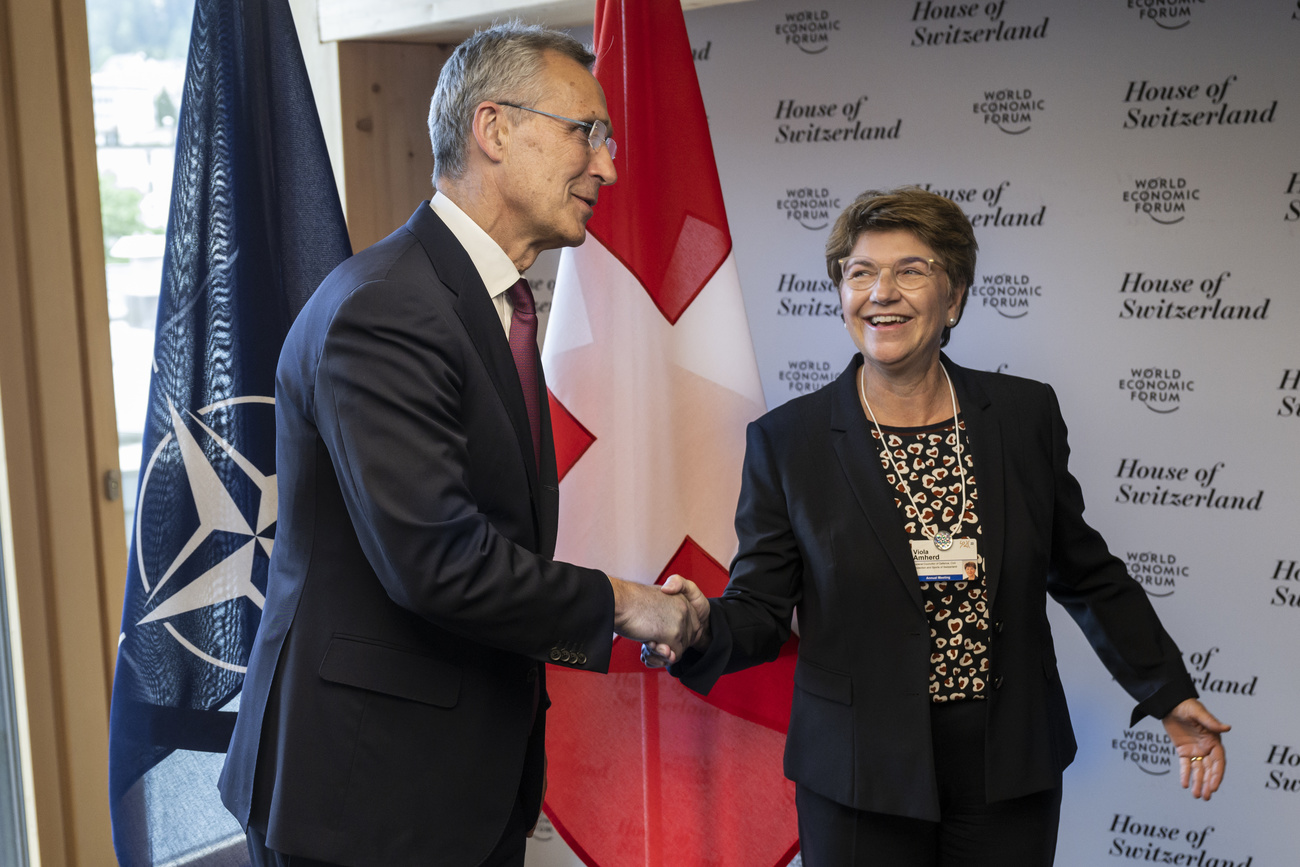 Handshake von Viola Amherd und Jens Stoltenberg vor den Flaggen von Nato und der Schweiz