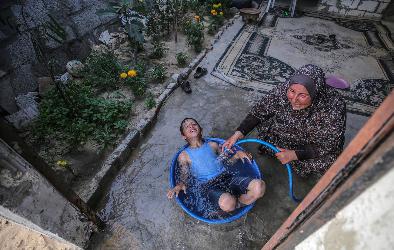 Femme baignant un enfant avec un tuyau dans une bassine