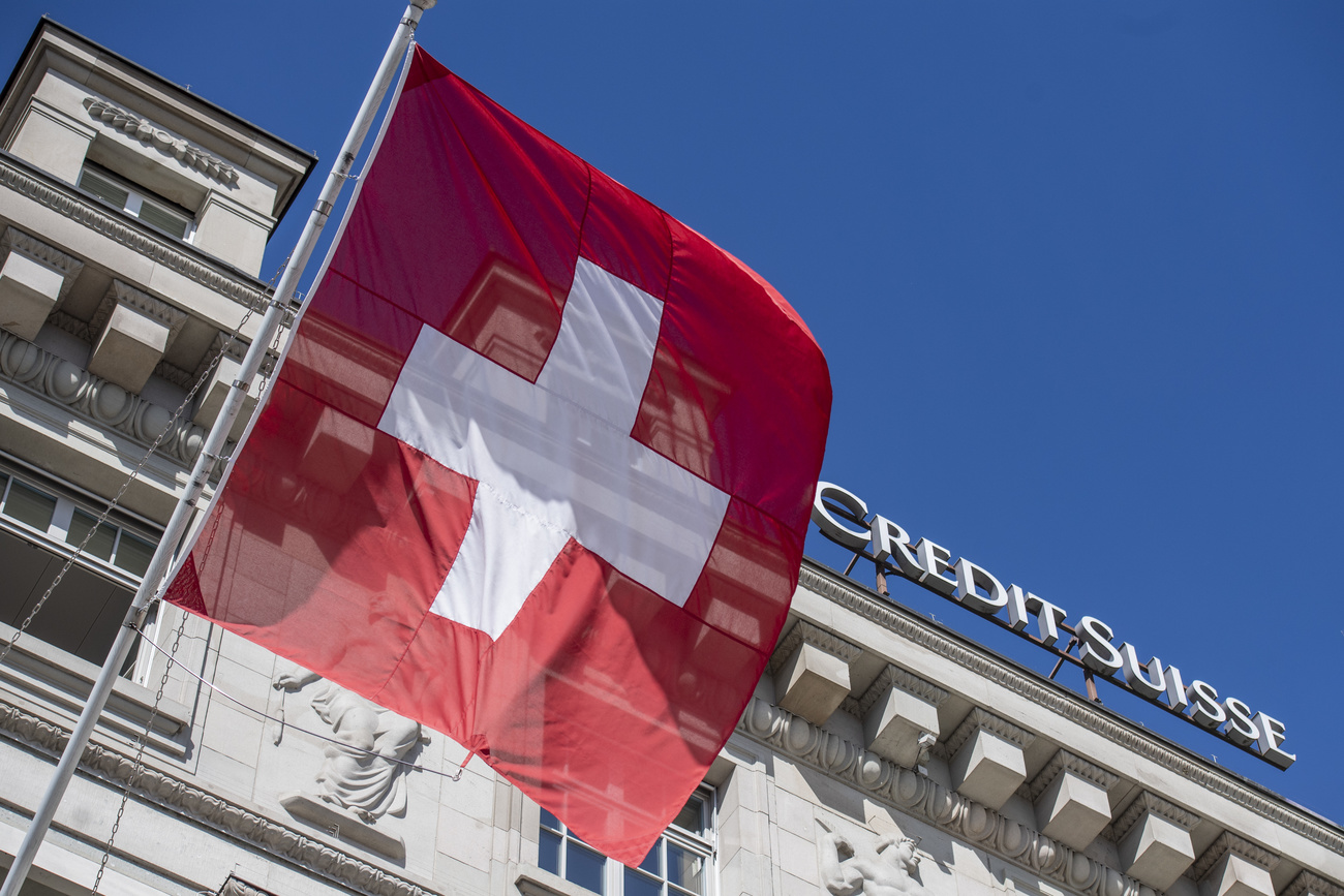 La bandera suiza ondea junto al logotipo de Credit Suisse