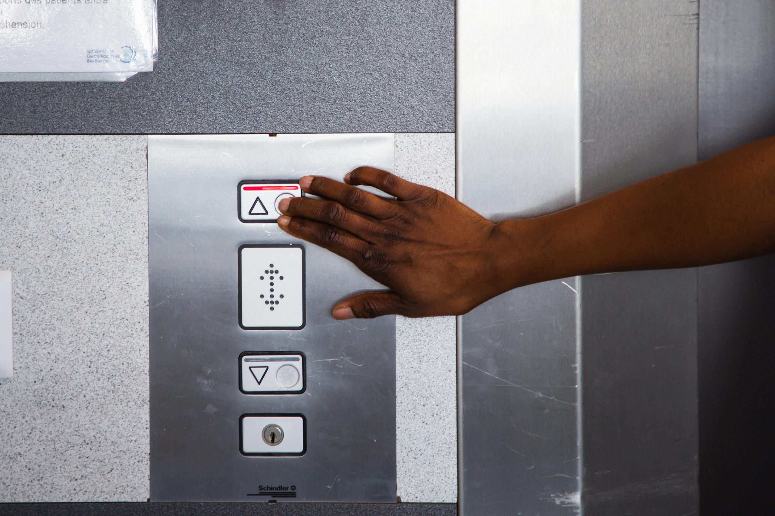 Finger drückt Knopf in einem Lift