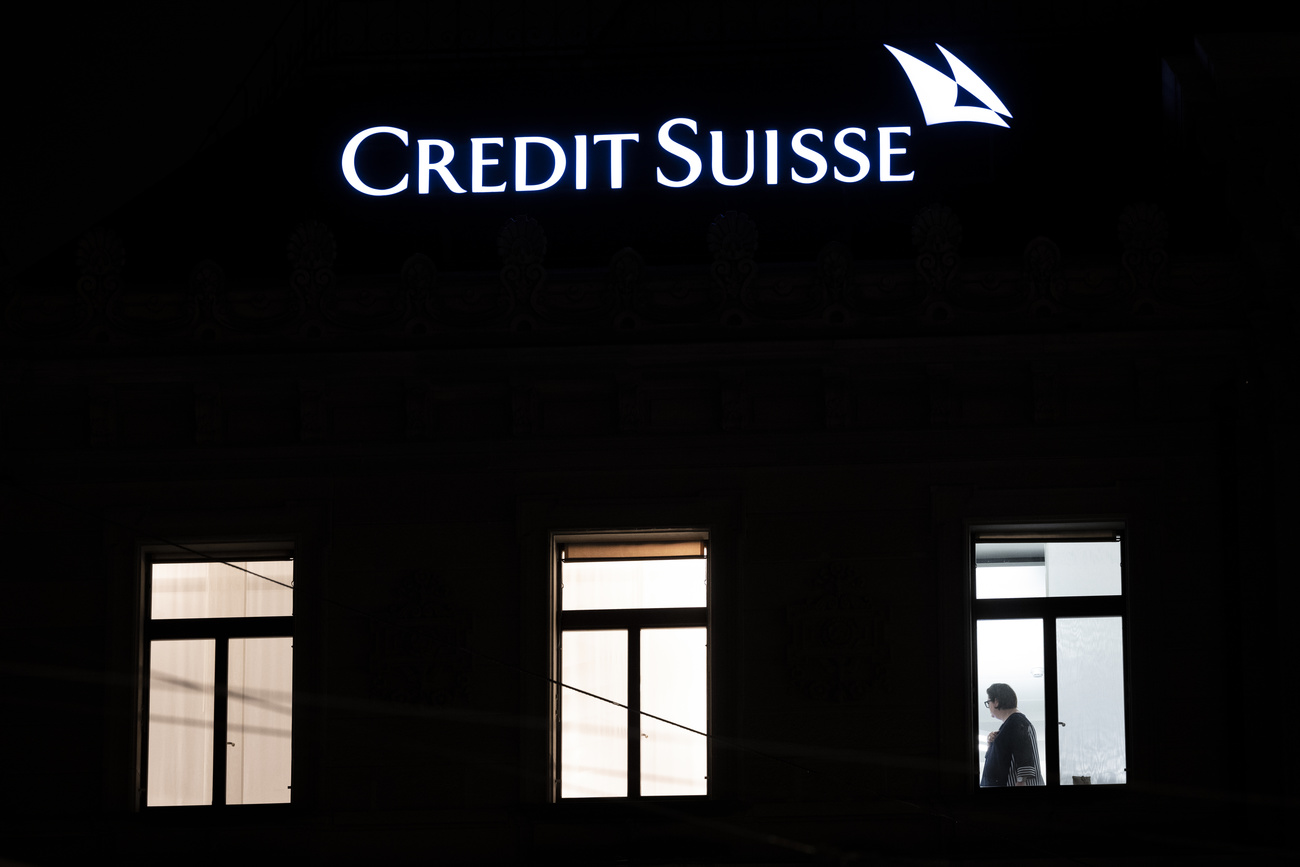 edificio di notte, tre finestre illuminate, scritta Credit suisse illuminata sopra le finestre