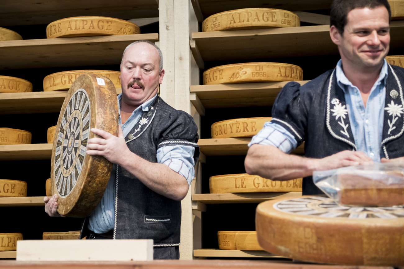 Due uomini vestiti in costume con il formaggio Gruyère sui scaffali.