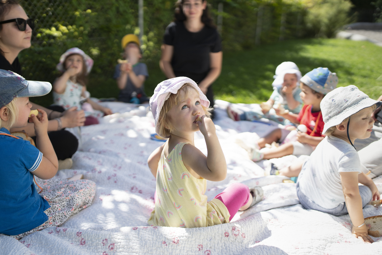 Groupe de sept enfants gardés par deux femmes en extérieur