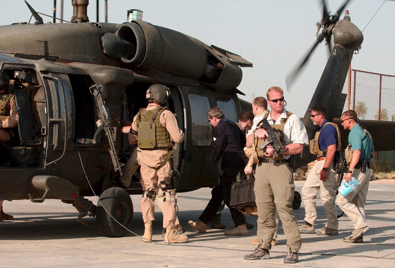一張拍攝於2007年6月17日的照片顯示美國黑水安保公司的工作人員正在伊拉克城市希拉登上直升機。 2007年9月16日的一次交火事件中，八名平民慘遭殺害，於是伊拉克政府吊銷了這家美國私人安保公司的執照，該公司是伊拉克當地最為知名的私營安保公司之一。