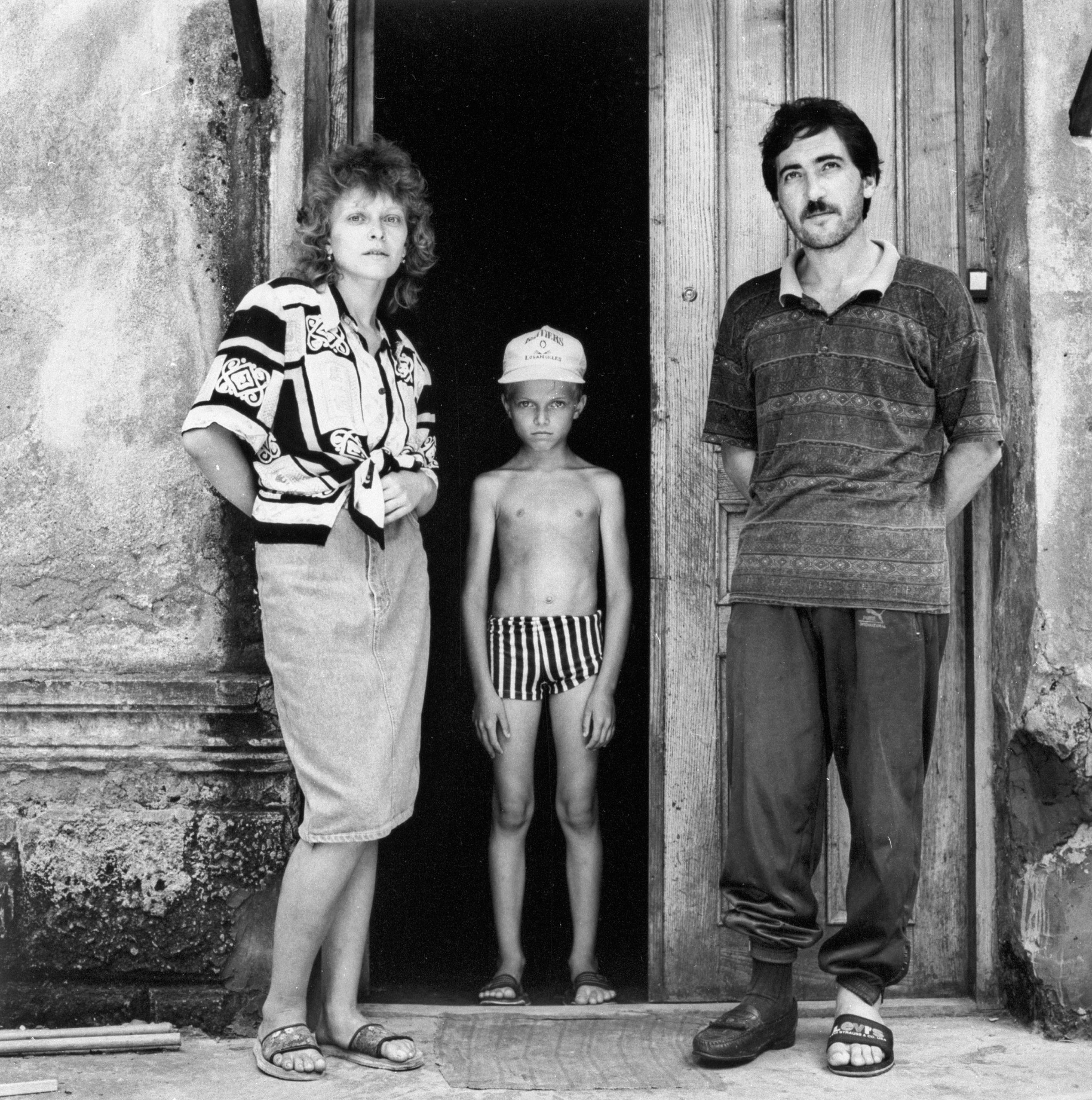Black and white photo of a woman, a young boy and a man in front of a door during the conflict between Abkhazia and Georgia.