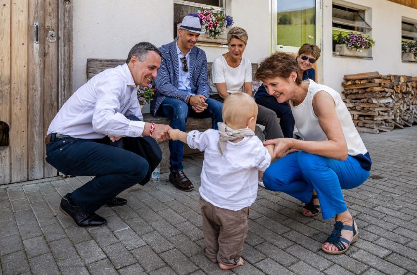 Fünf Erwachsene begrüssen ein kleines Kind