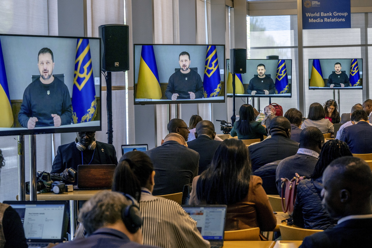 モニターでスピーチをするウクライナのゼレンスキー大統領とメモを取る記者ら