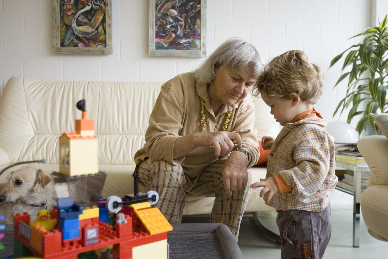 una donna anziana gioca con un bambino piccolo in un salotto