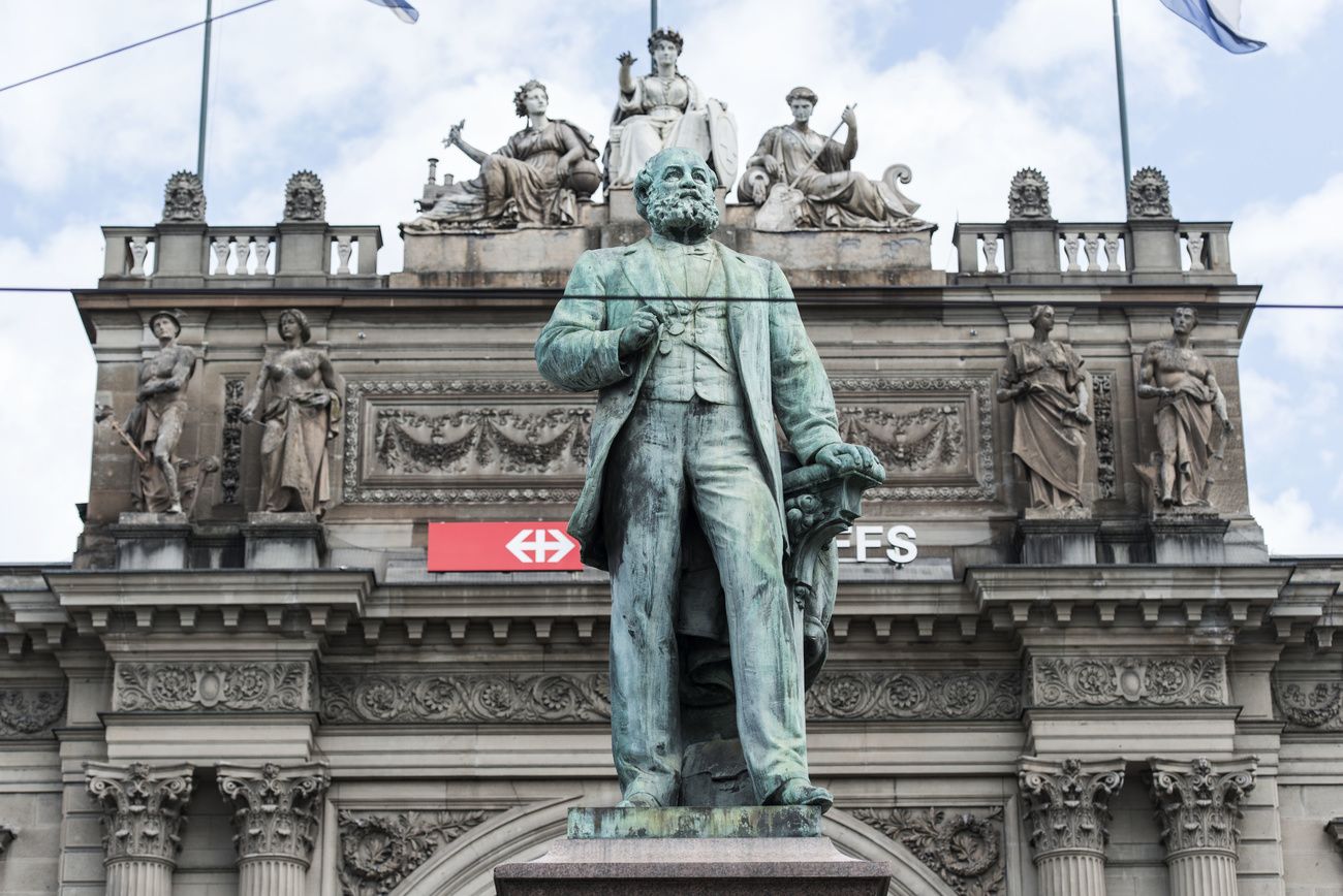 Grosse Bronzestatue eines Manns vor einem Bahnhof