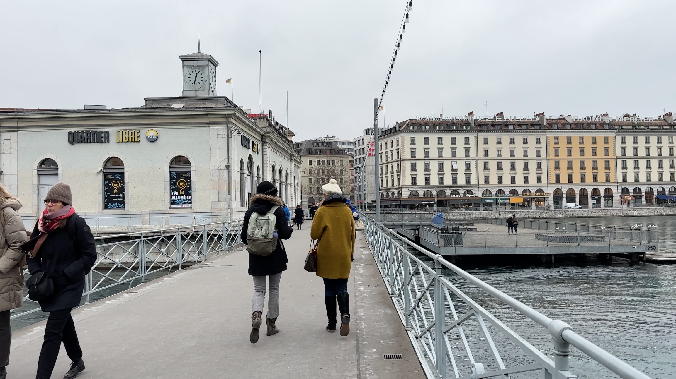 Две женщины идут по Женеве по мосту через реку