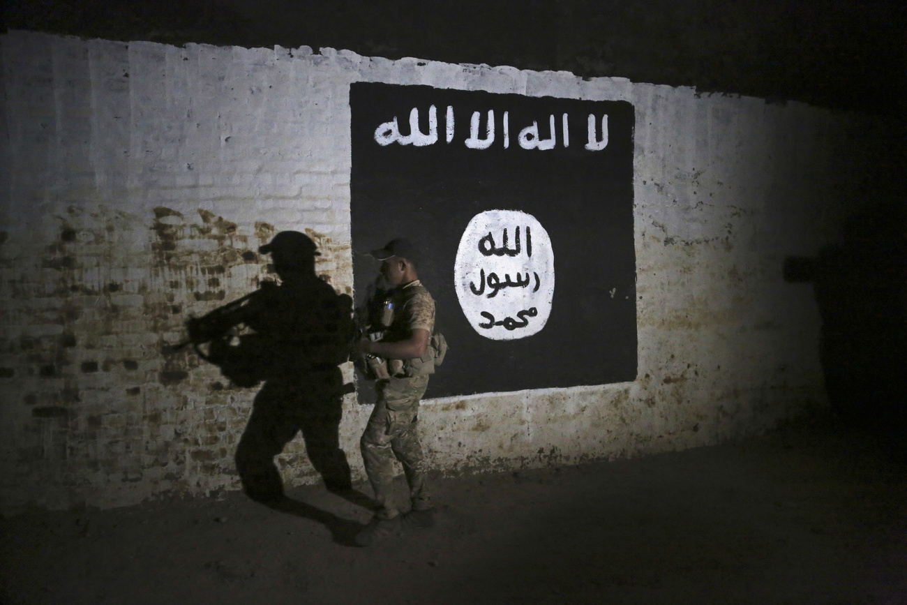 Soldier walks by Islamic State mural