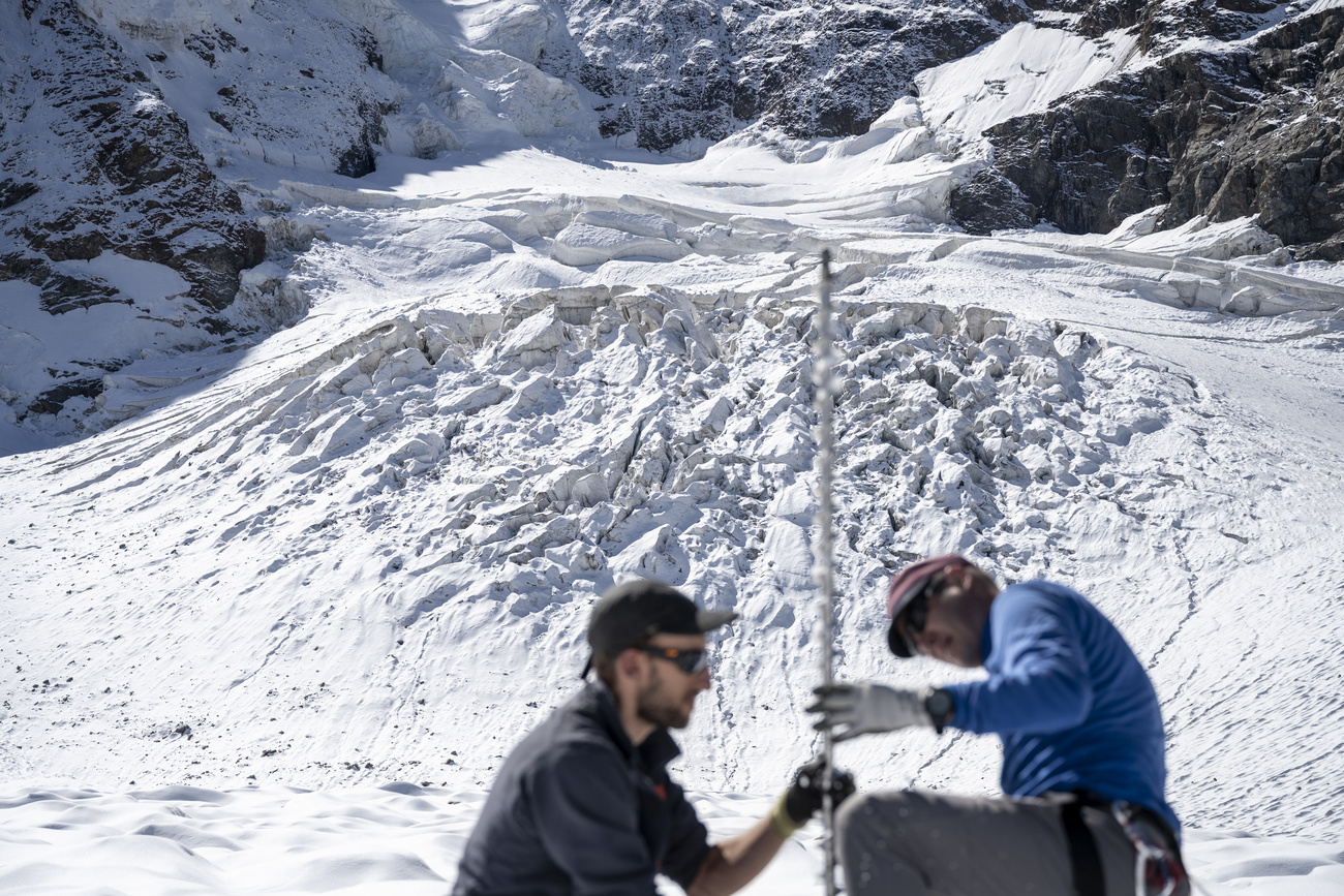 El equipo GLAMOS mide la capa de nieve en un glaciar alpino