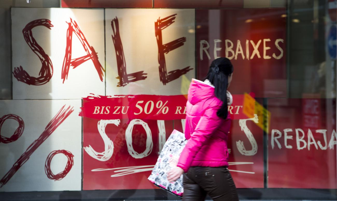 Una donna davavnti a una vetrina di un grande magazzini con i saldi.