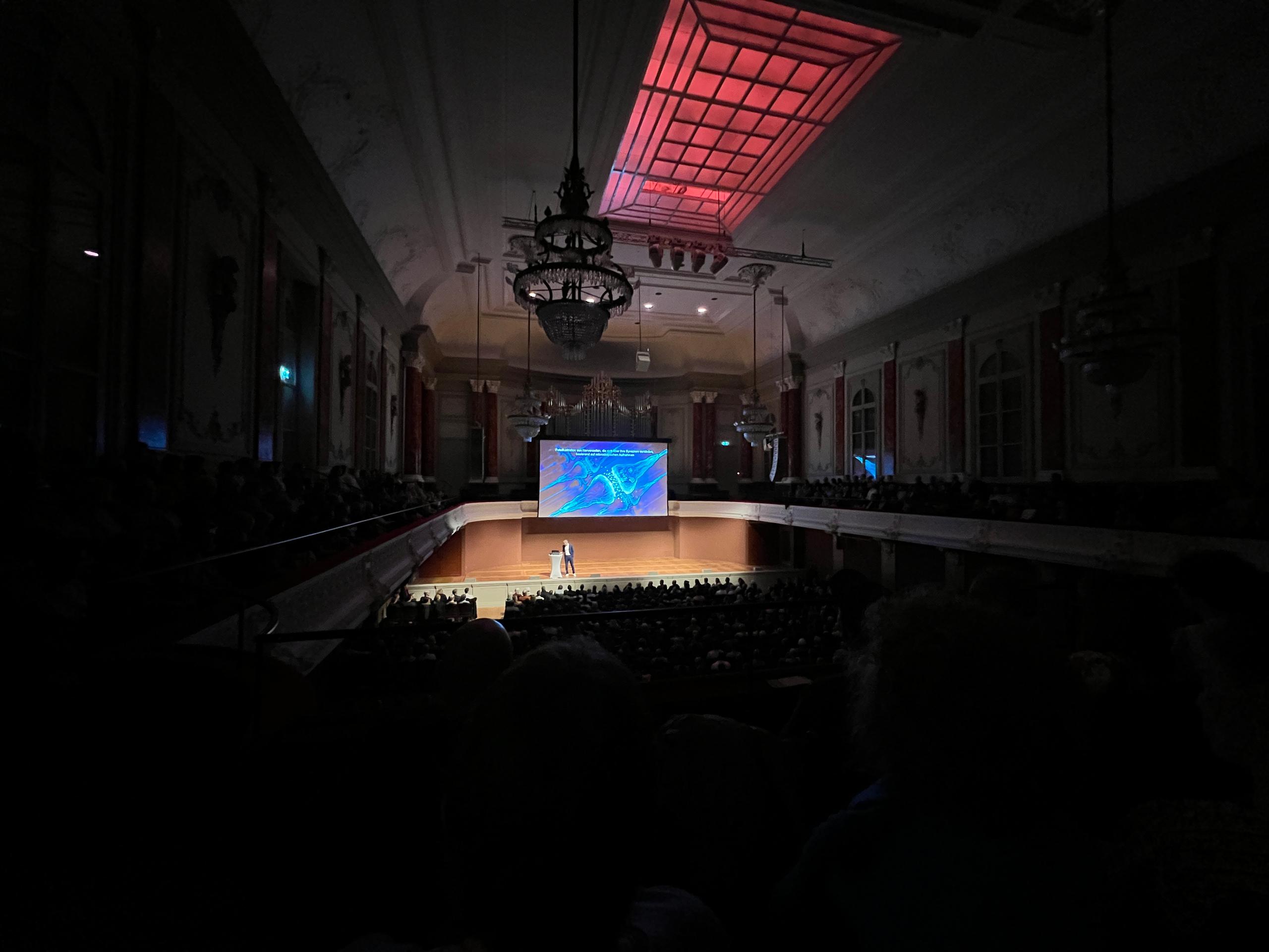 sala riempita di persone che assistono a una presentazione di un uomo