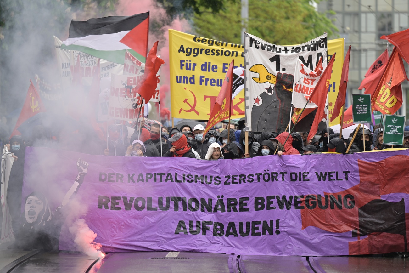 Demonstrationszug mit Bannern und Fahnen und Rauchpetarden