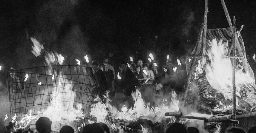 Gruppe von Menschen, die um ein grosses Feuer herum stehen