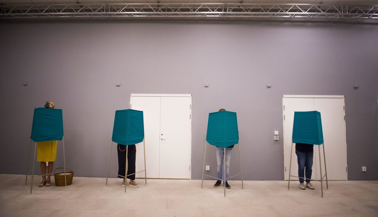 Vier Menschen wählen in Wahlstationen mit verdeckten Gesichtern.