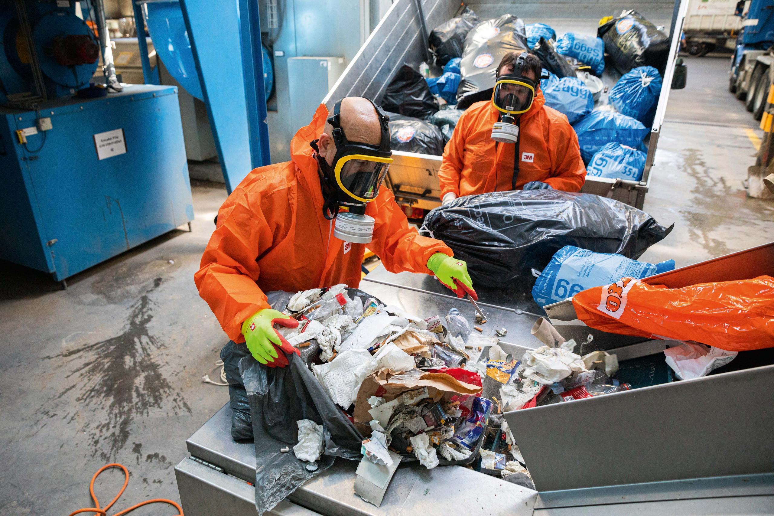 Un hombre con mascarilla y traje de plástico trabajando con desechos en un vertedero