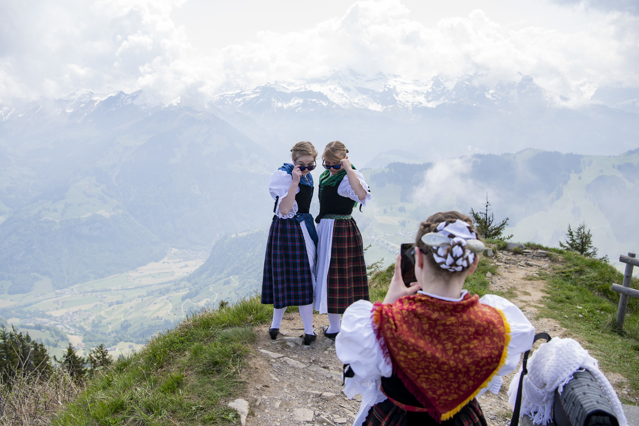 Women dressed in traditional Swiss costume pose for photos.