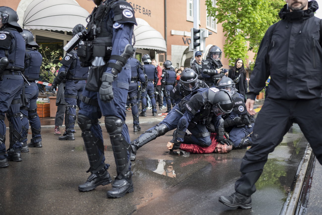 La polizia mentre ferma a terra un manifestante.