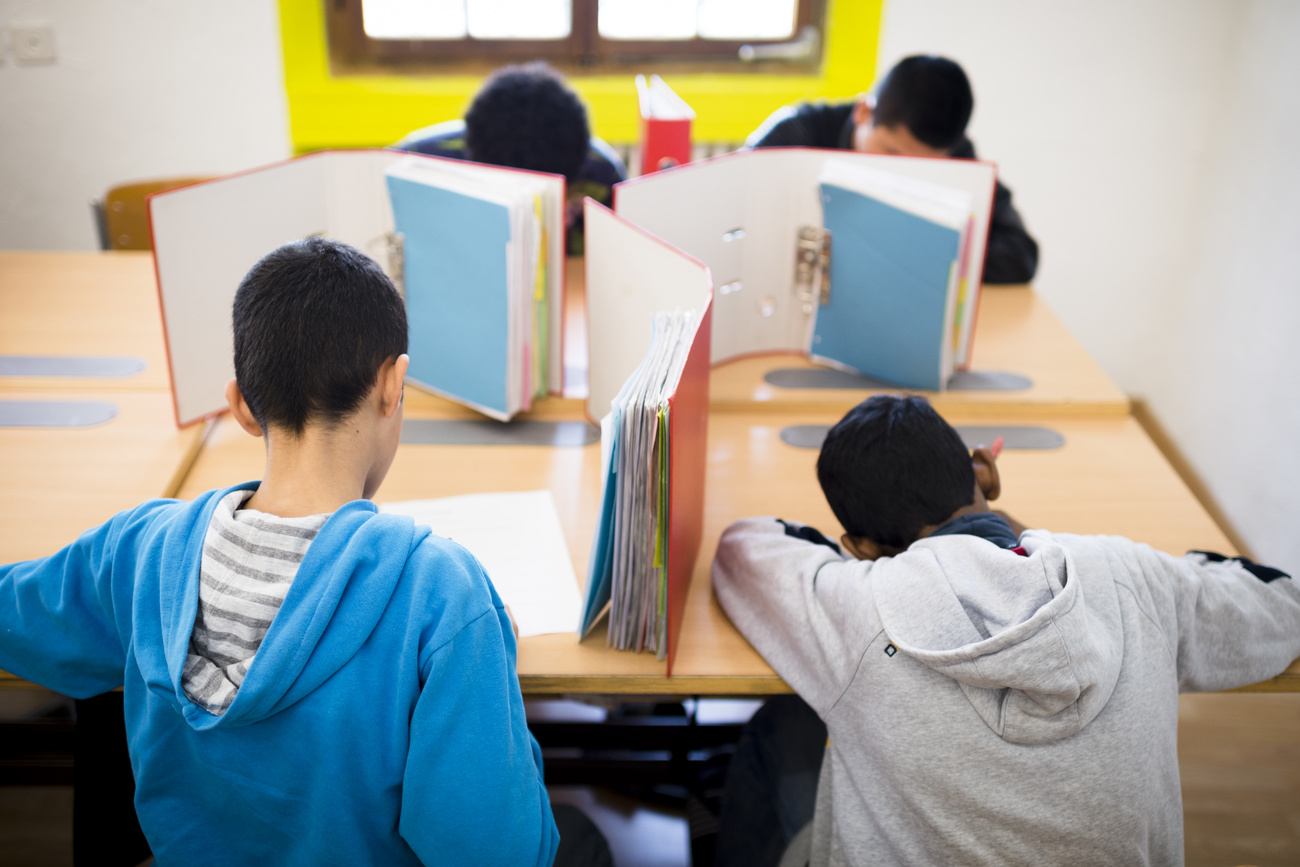Vier Schüler schreiben an Schulpulten