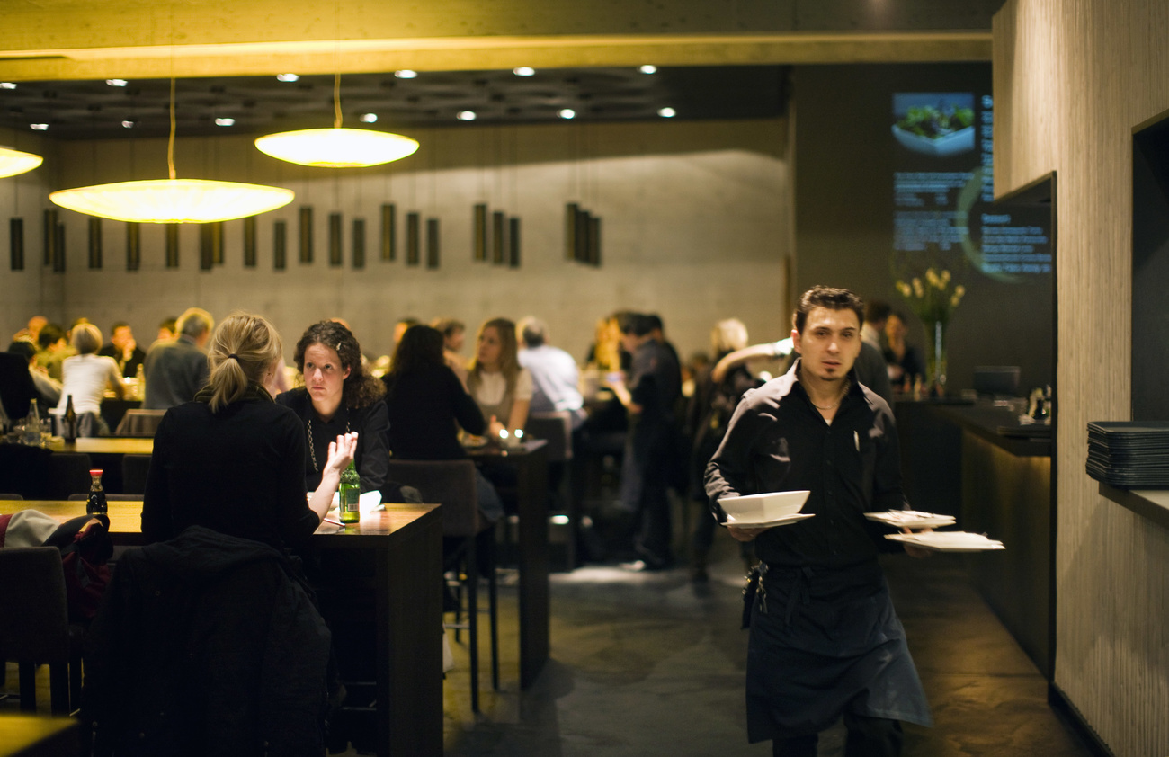 Un cameirere con i piatti in mano mentre serve in un ristorante a Basilea.