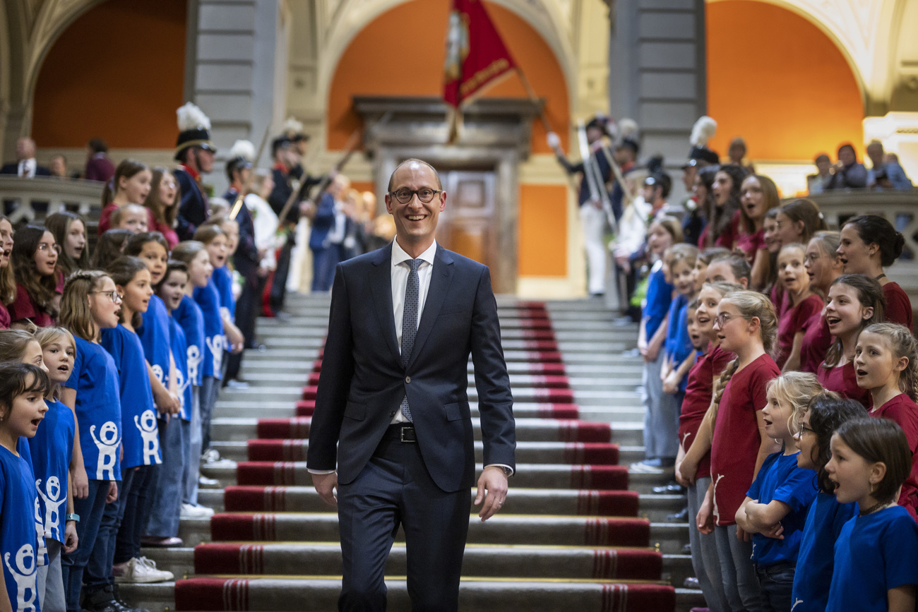 Il presidente del Consiglio nazionale Martin Candinas mentre scende le scale con attorno i bimbi del coro di Sumvitg.