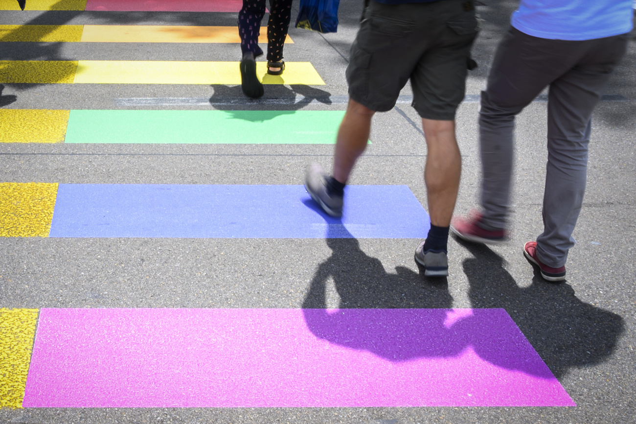 Foto de un paso de peatones arco iris con gente caminando
