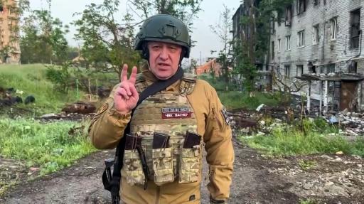 Un hombre con uniforme militar se para en un edificio destruido.