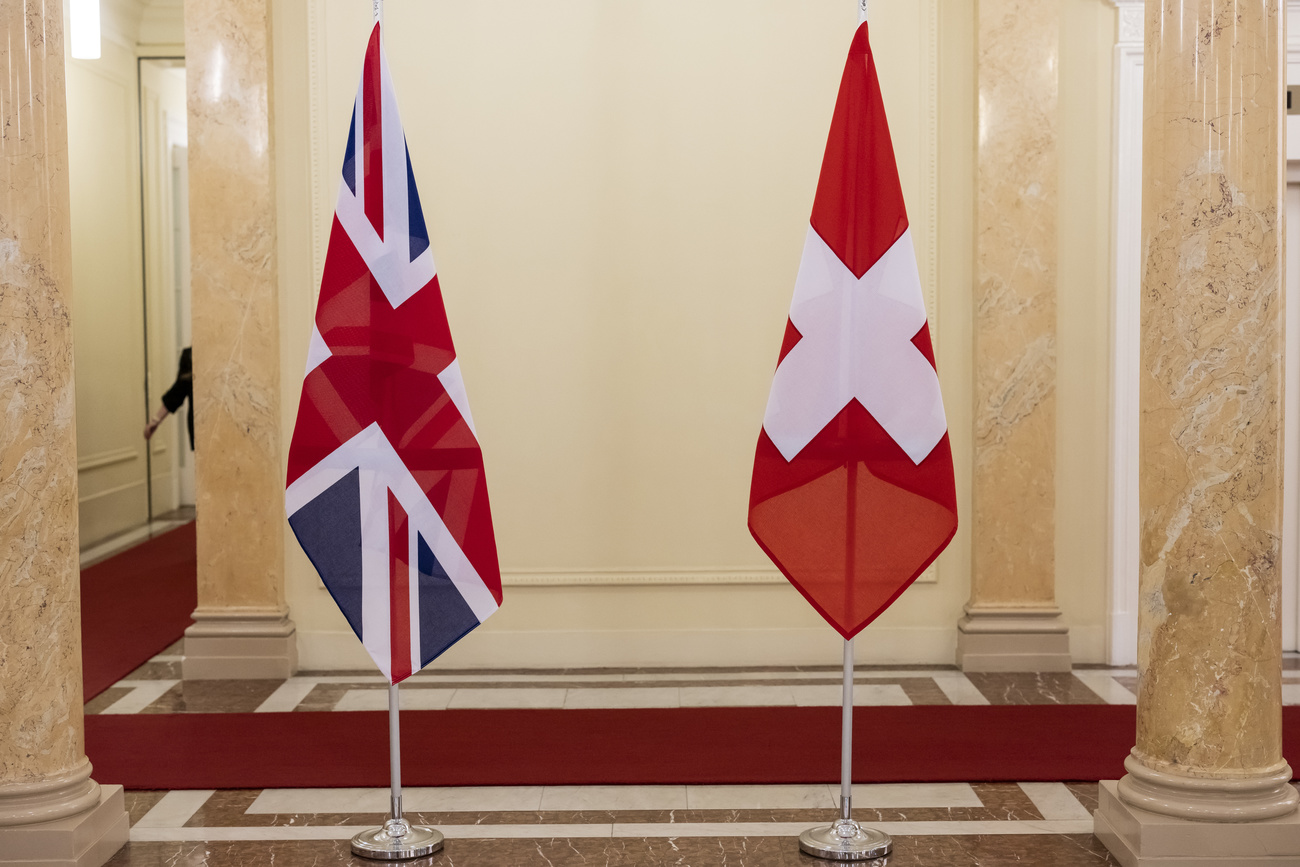 The Union Jack and the Swiss flag are displayed during a bilateral meeting between Swiss and UK delegations.
