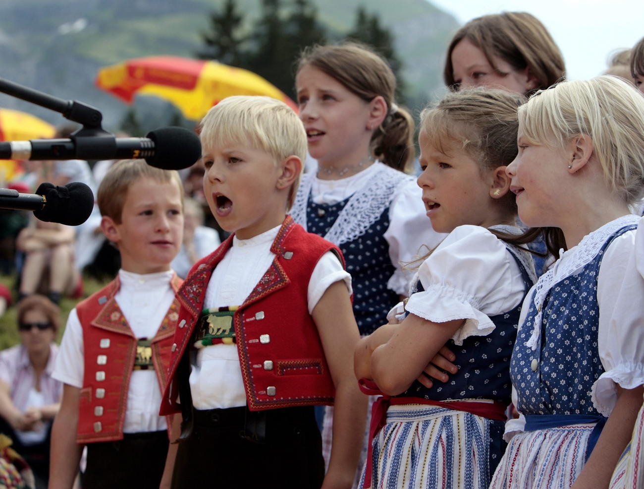 Kinder tragen eine Tracht und singen.