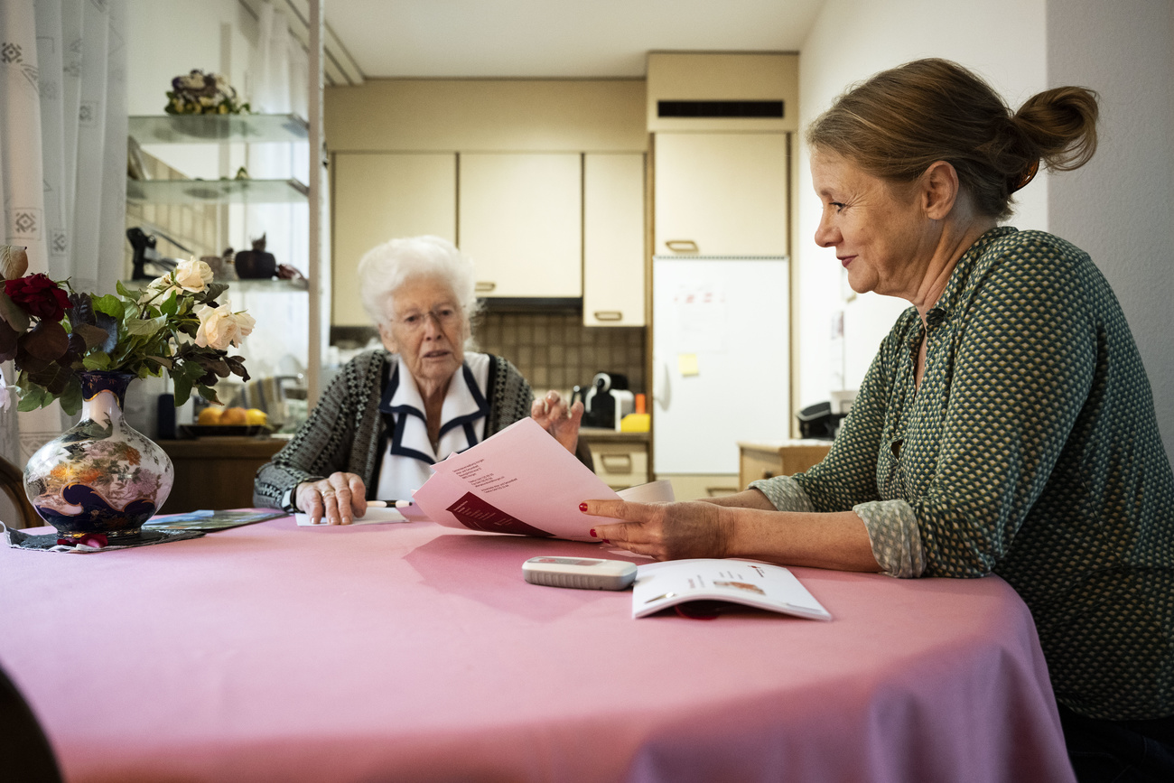 Photo of a woman showing papers to an elderly woman on a table