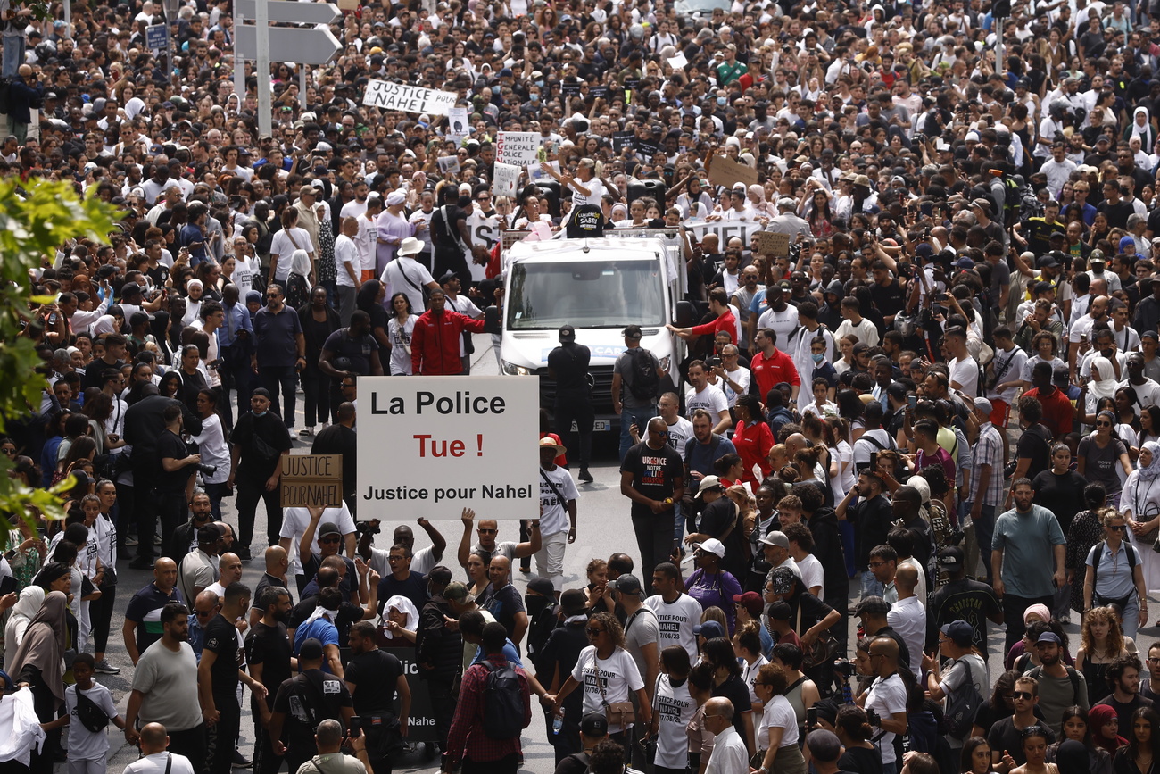 Il corteo a Nanterre con un cartello con la scritta: La polizia uccide.