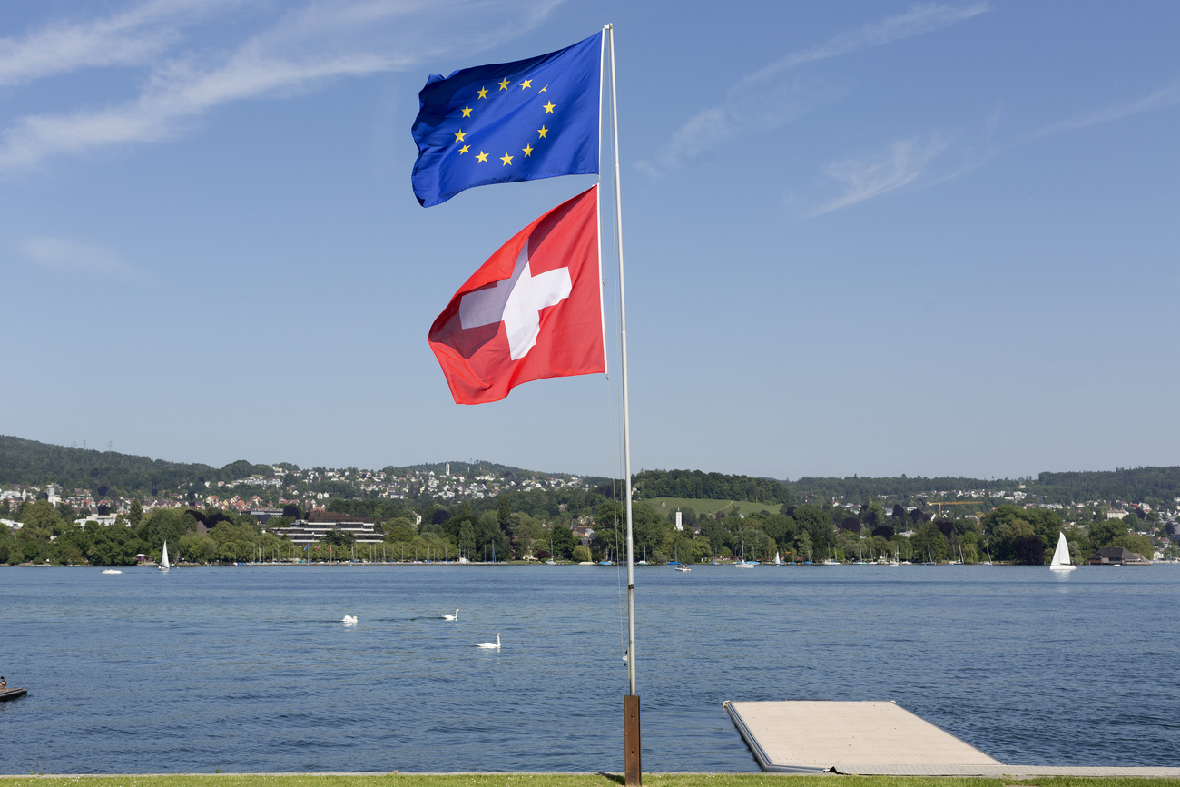 Eine EU-Flagge und eine Schweizerfahne flattern übereinander im Wind